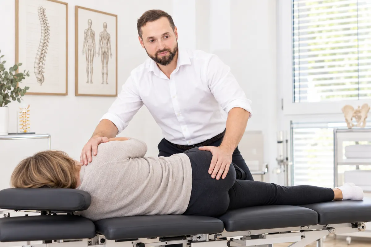 KI-Illustration: R. Beyer bereitet eine chiropraktische Behandlung der ISG-Region in Seitenlage vor.